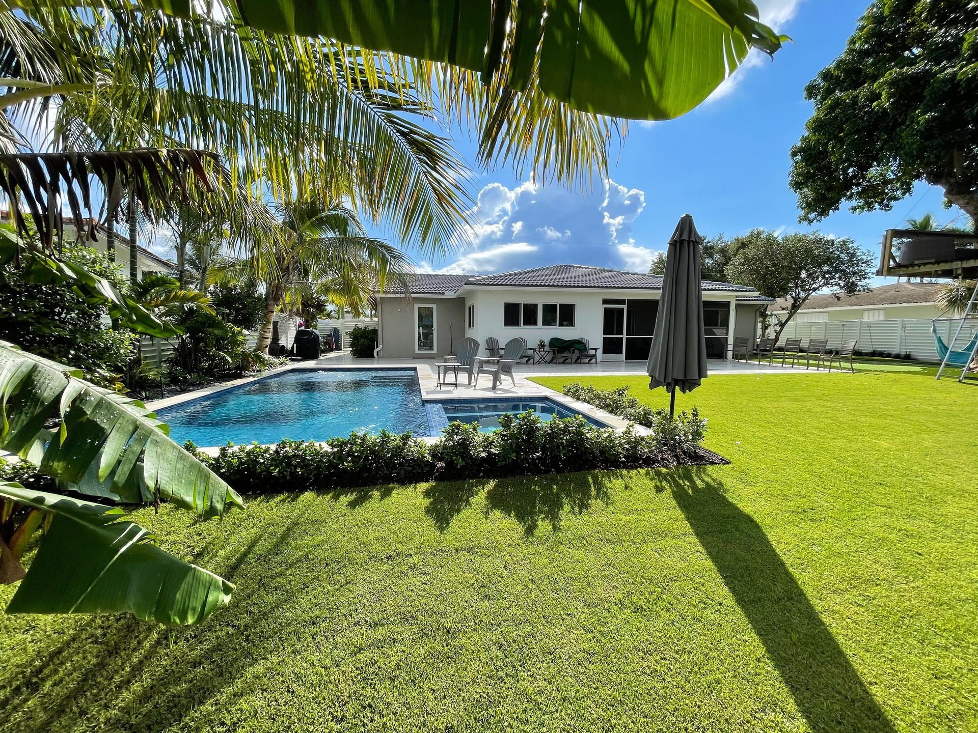 Professional landscape maintenance at a Boca Raton residential home with brick driveway and lush plantings
