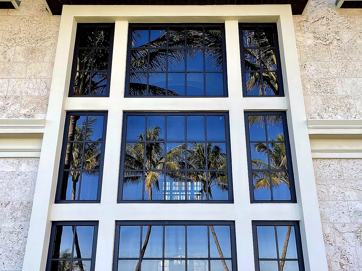 Estate with crystal clear windows reflecting palms and blue sky