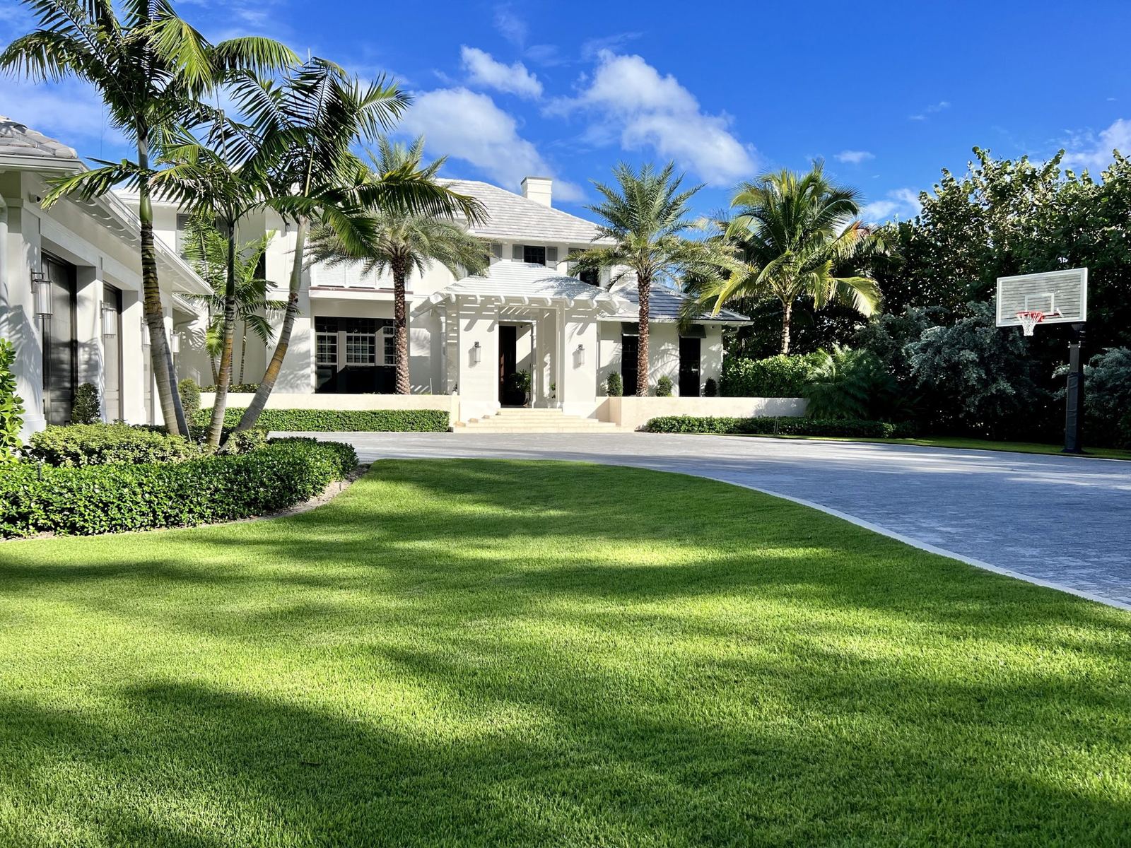 Coastal South Florida estate with manicured front lawn, palms and paver drive