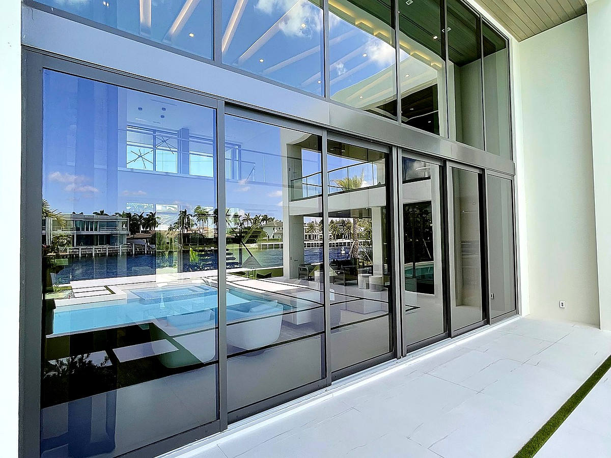 Crystal clear exterior glass reflecting pool and sky at South Florida estate