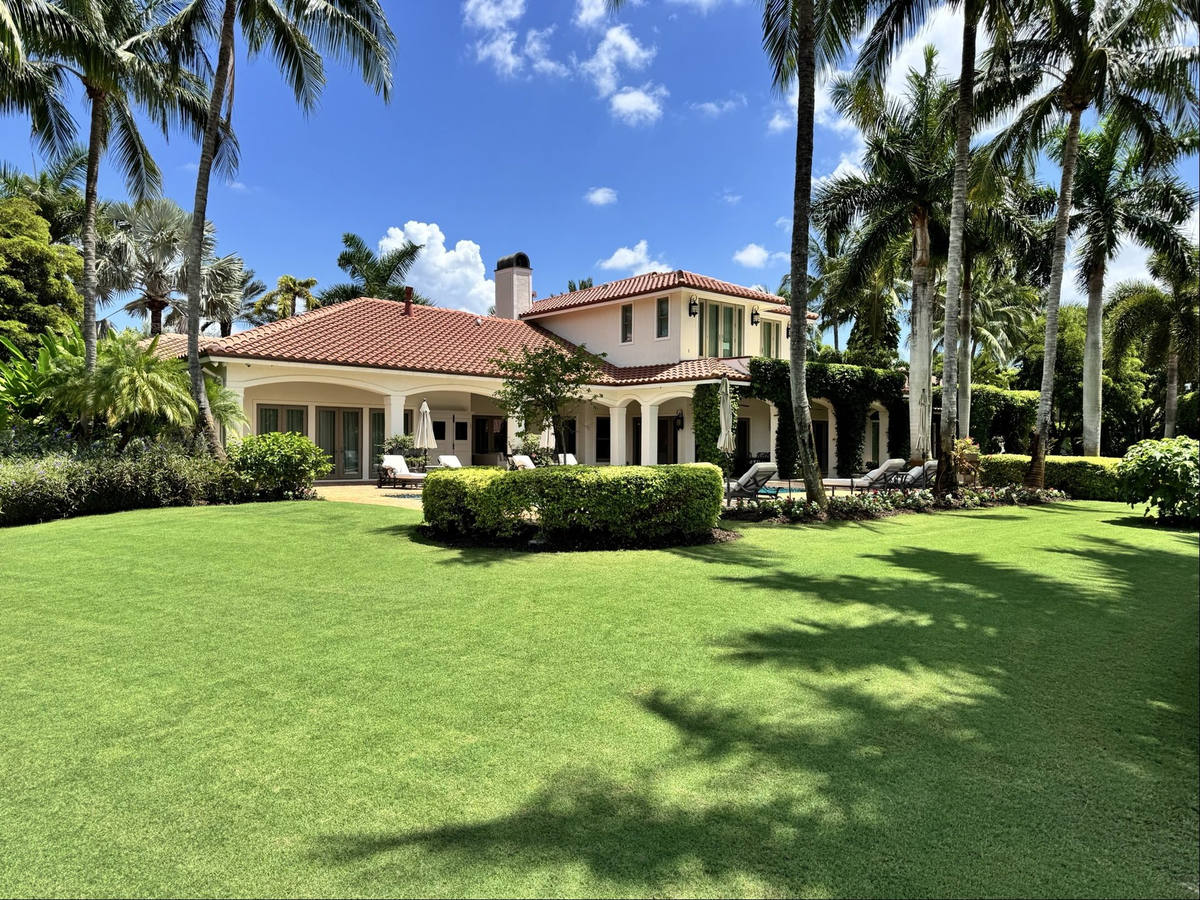 Reel mowed lawn at residential property with trimmed hedges and palms in South Florida