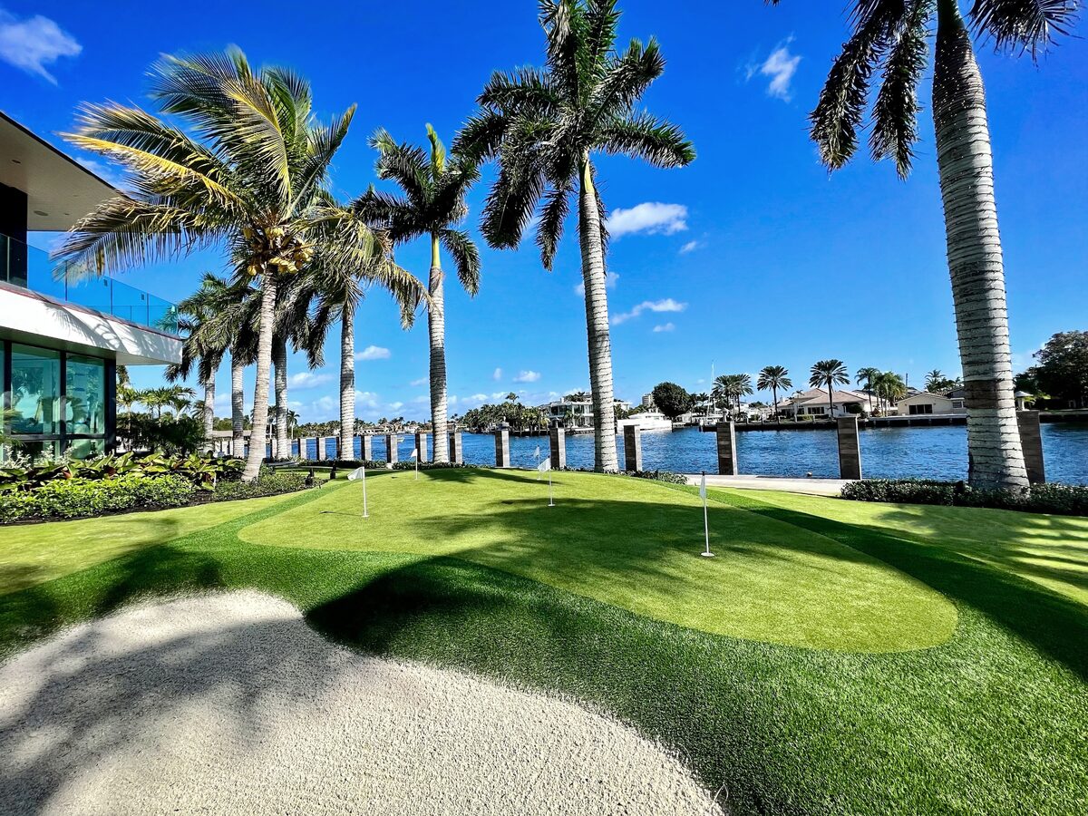 Modern Intracoastal estate with palm-lined paver-and-turf walkway, hedges, and waterfront pool — Coastal Smart Property Care by Florida Boys