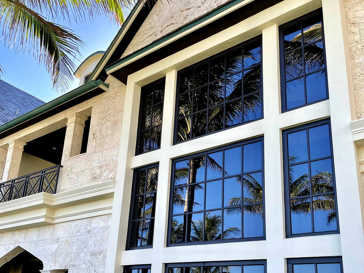 Highland Beach oceanfront estate with pristine grid windows reflecting palms and coastal sky