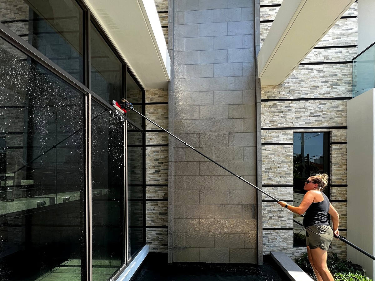 Professional window cleaning with water-fed pole system at luxury Boca Raton estate with fountain pool