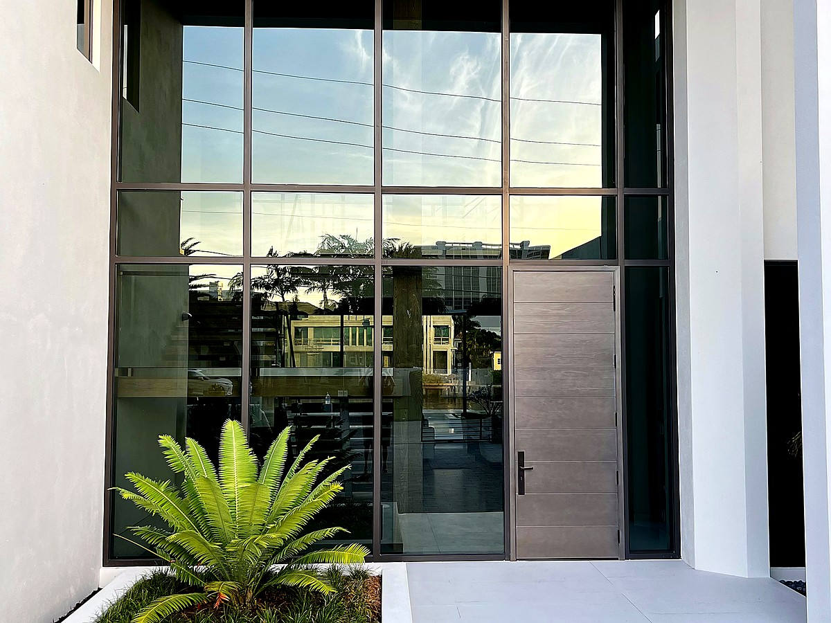 Modern coastal entry with impact glass windows and tropical plantings near Pompano Beach