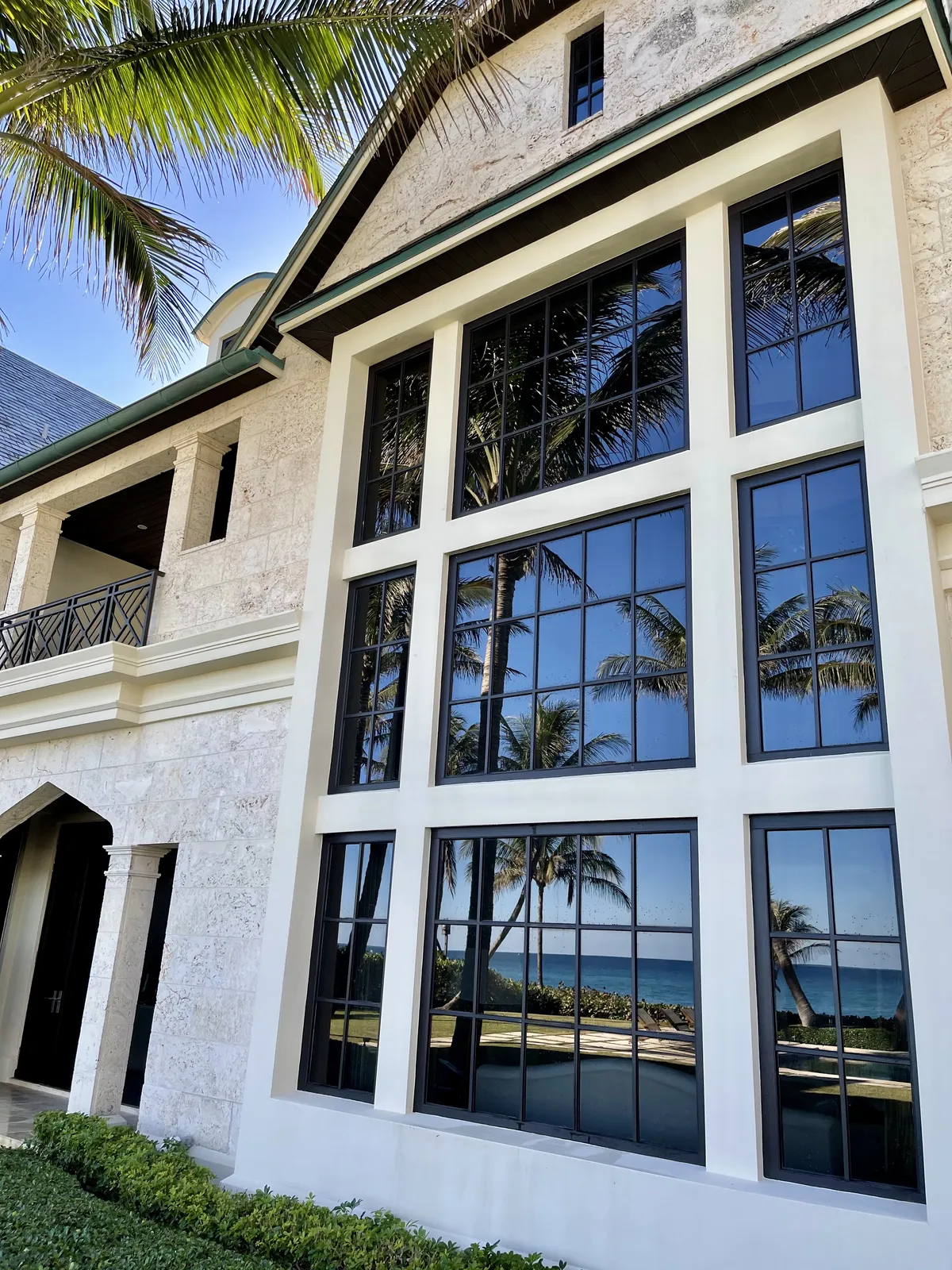 Grid windows reflecting palms and ocean at Highland Beach home