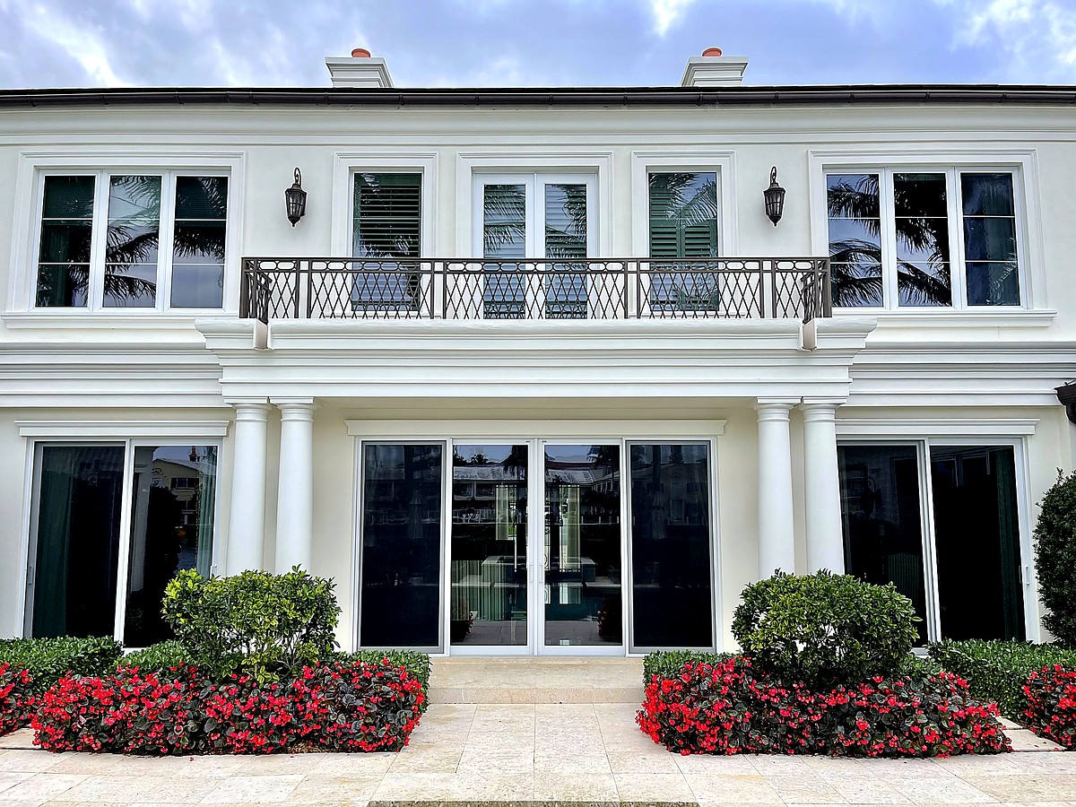 Two-story estate windows with crystal clear palm reflections after professional cleaning in Boca Raton