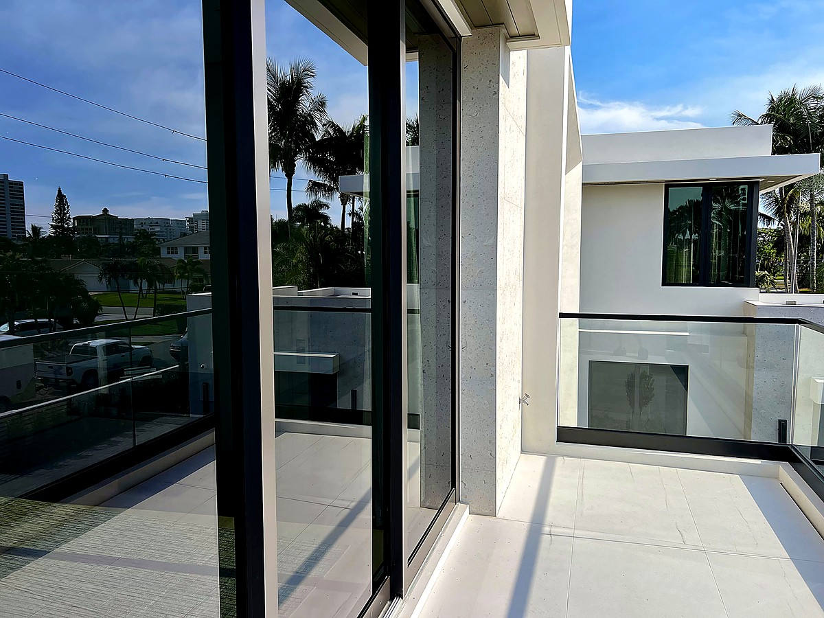 Second-story balcony with pristine glass panels at modern coastal home near Deerfield Beach