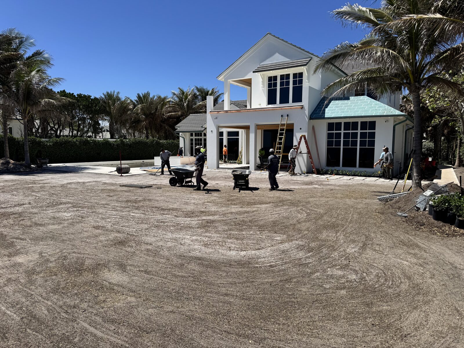 Crew grading and prepping soil with wheelbarrows before sod installation in South Florida