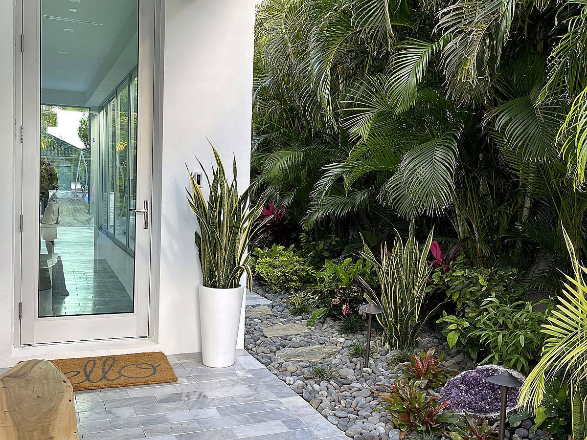 Tropical entry with glass door and lush landscaping in Delray Beach
