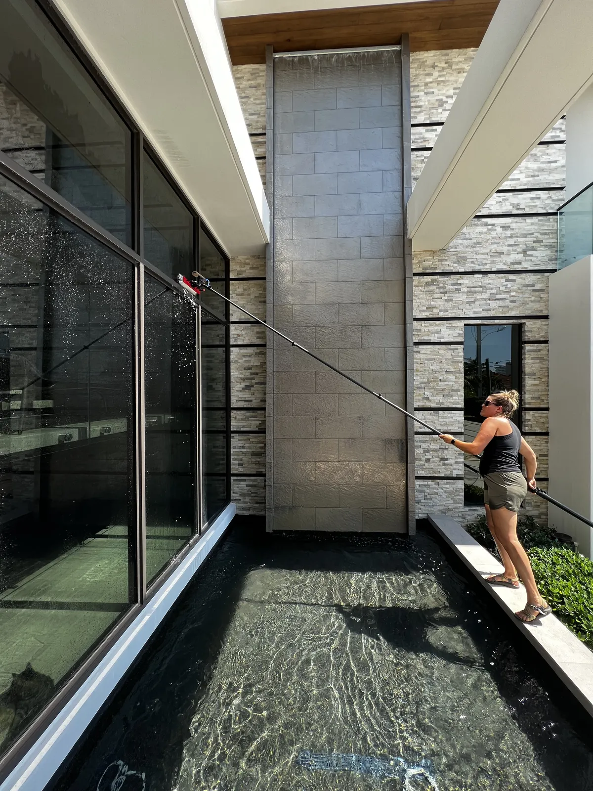 Water-fed pole cleaning impact windows over fountain at Boca Raton home